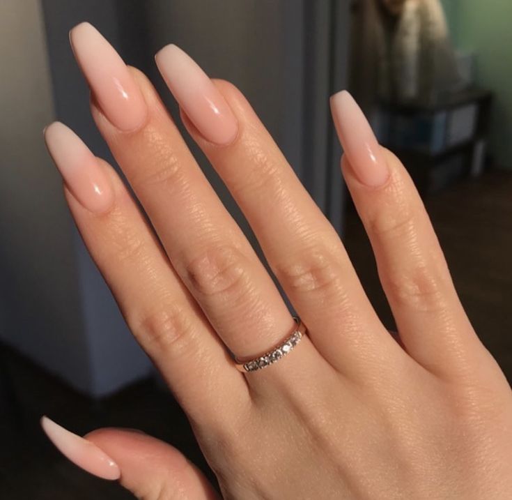 a woman's hand with long almond nails and a ring on her left hand