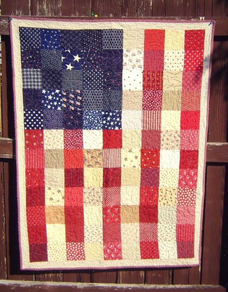 an american flag quilt hanging on a wooden fence