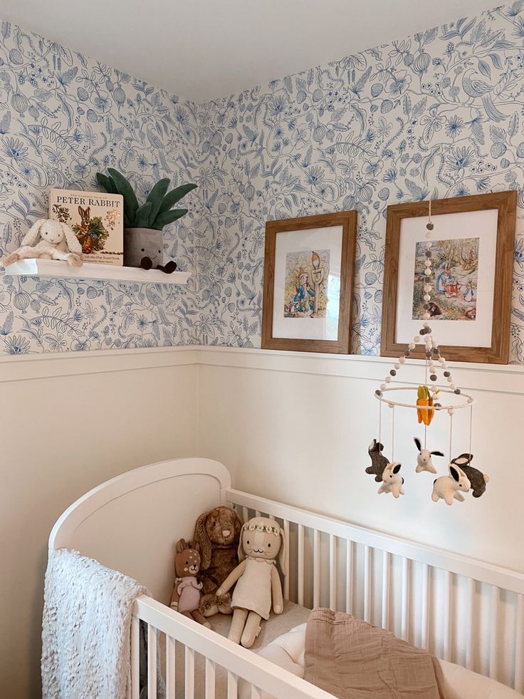 a baby's crib in a room with blue wallpaper and pictures on the wall