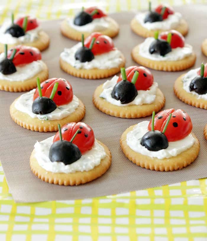 ladybug cookies with whipped cream and cherries are arranged on a baking sheet