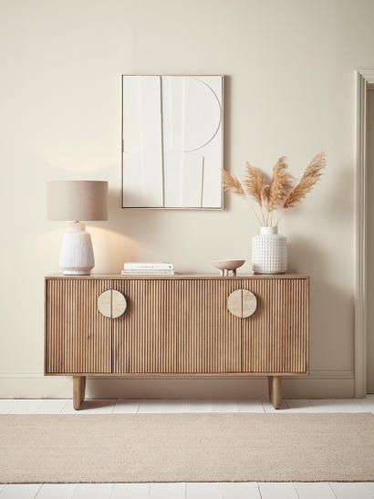 a white vase sitting on top of a wooden dresser next to a lamp and mirror