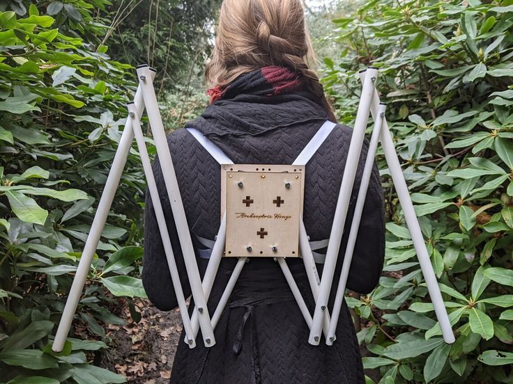 the back of a woman wearing a black coat with white crosses attached to her back