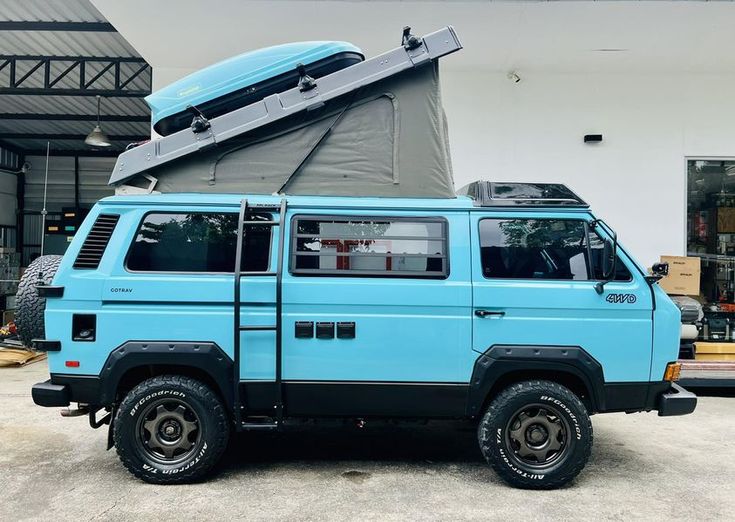 a blue van with an open roof sitting in front of a building