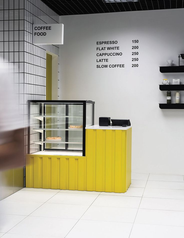 a yellow and black counter in a white room with shelves on the wall next to it