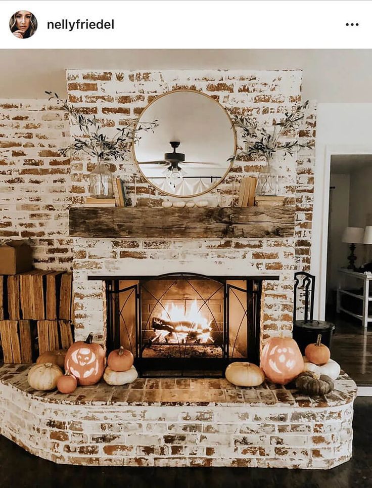 a brick fireplace with pumpkins on the mantle