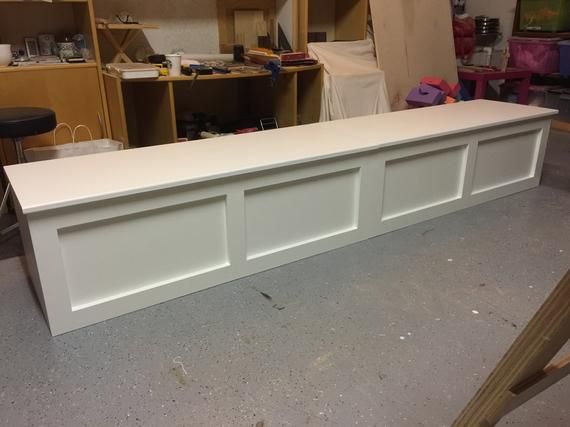 a white bench sitting in a room next to shelves