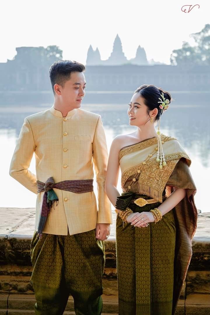 a man and woman standing next to each other in front of a body of water