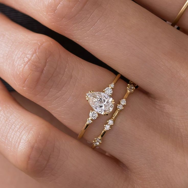 a woman's hand with two gold rings and one diamond ring on her finger