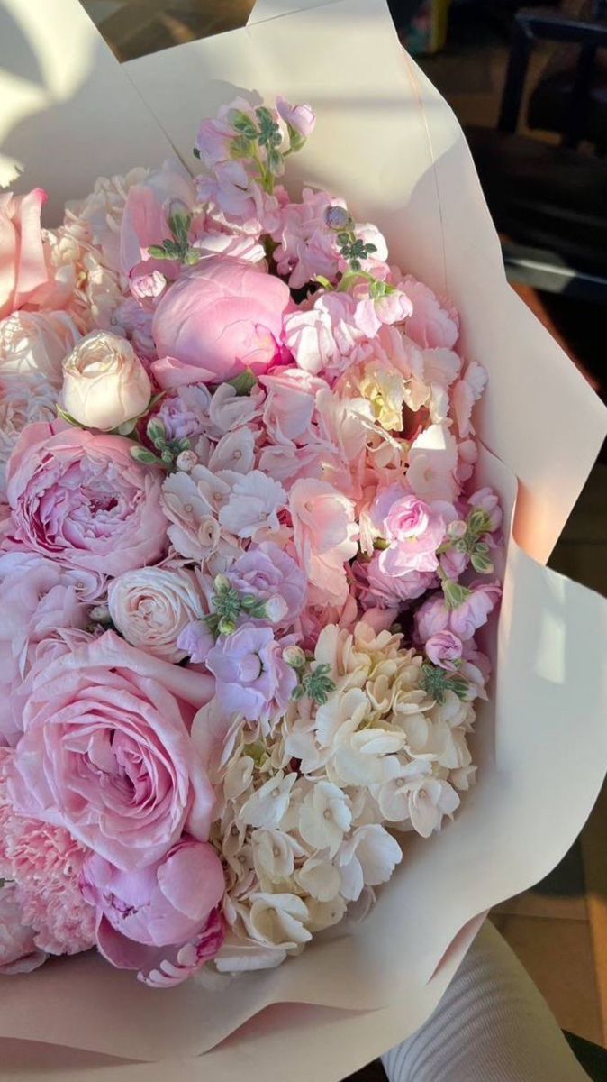 a bouquet of pink and white flowers in someone's hand