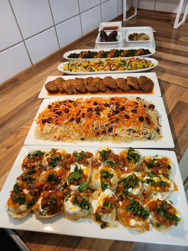 a table topped with lots of food on top of white trays filled with different types of food