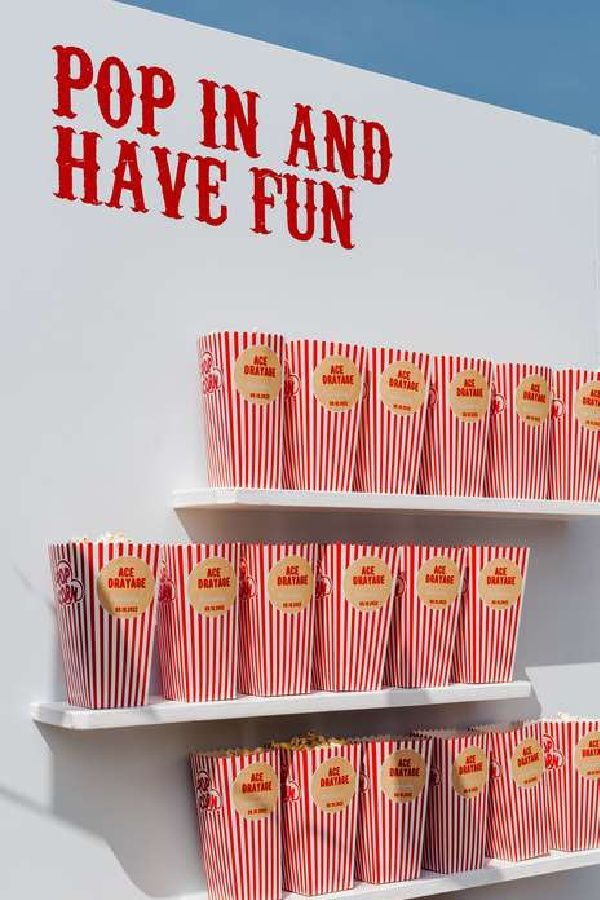 some red and white striped cups on a shelf with the words pop in and have fun