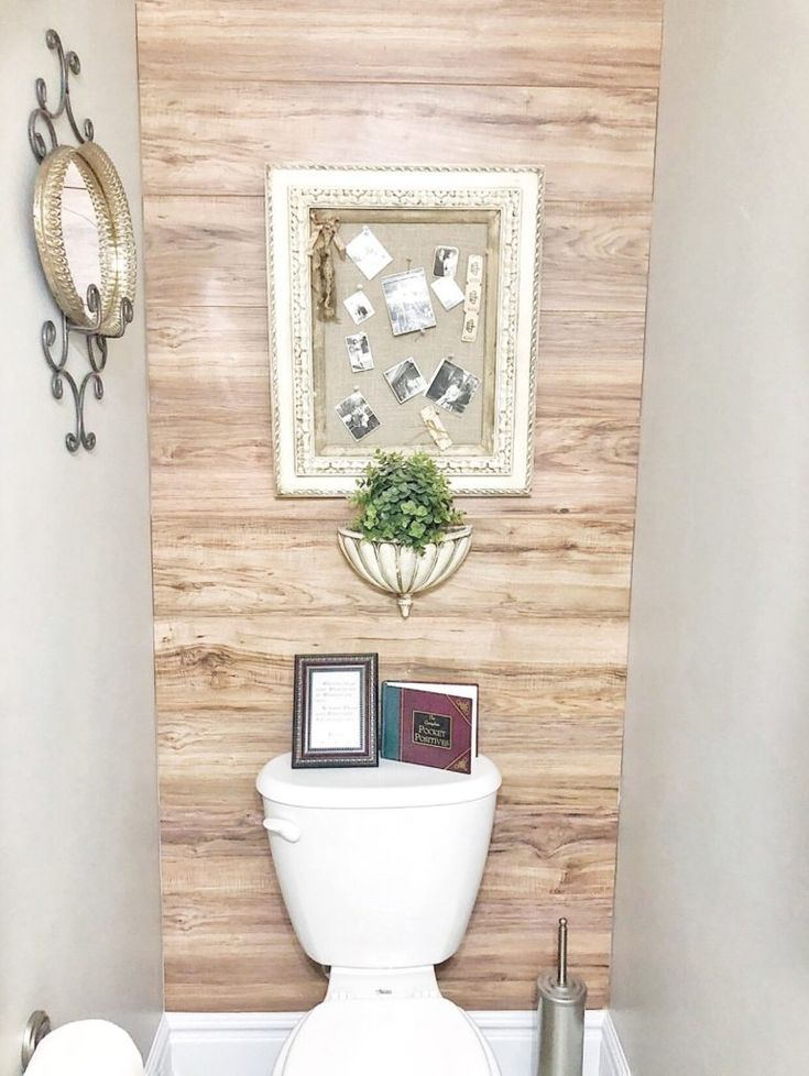 a white toilet sitting in a bathroom next to a wooden wall with pictures on it