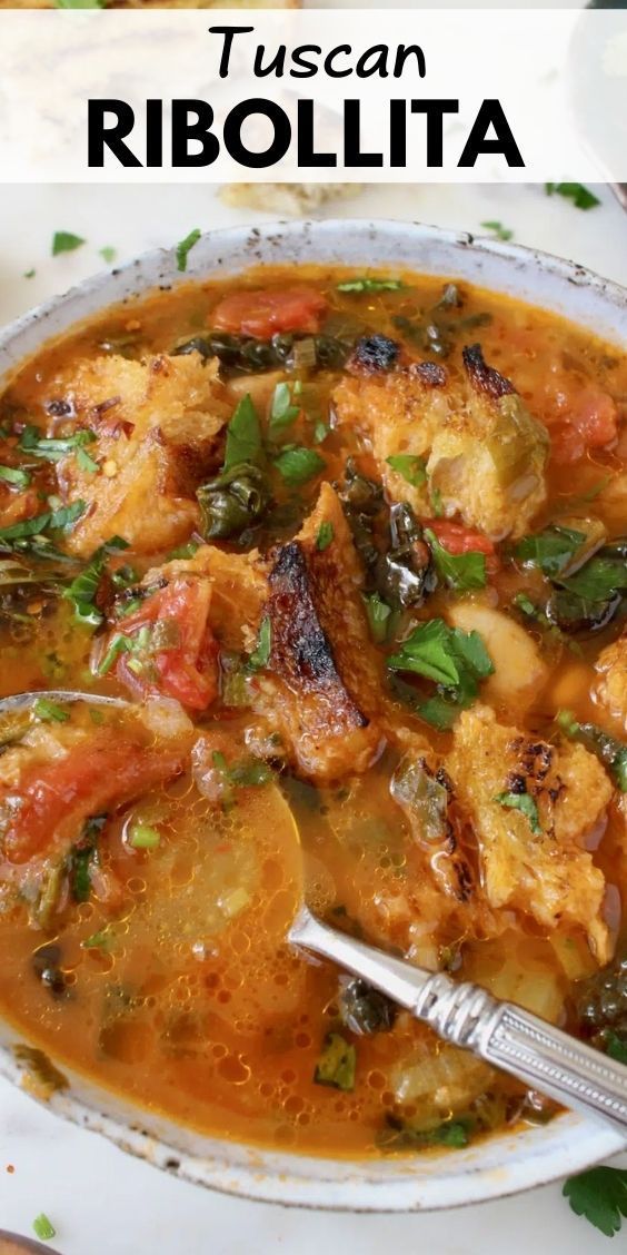 a white bowl filled with chicken and vegetable stew next to a plate of bread on the side