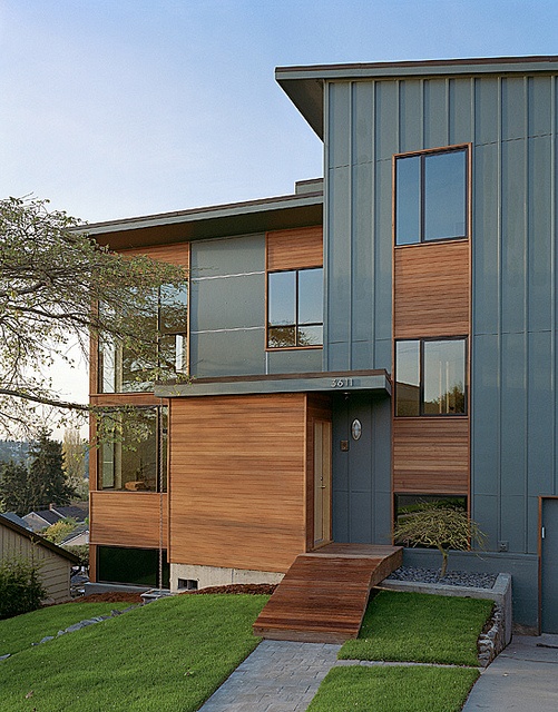 a modern house with grass and trees in the front yard