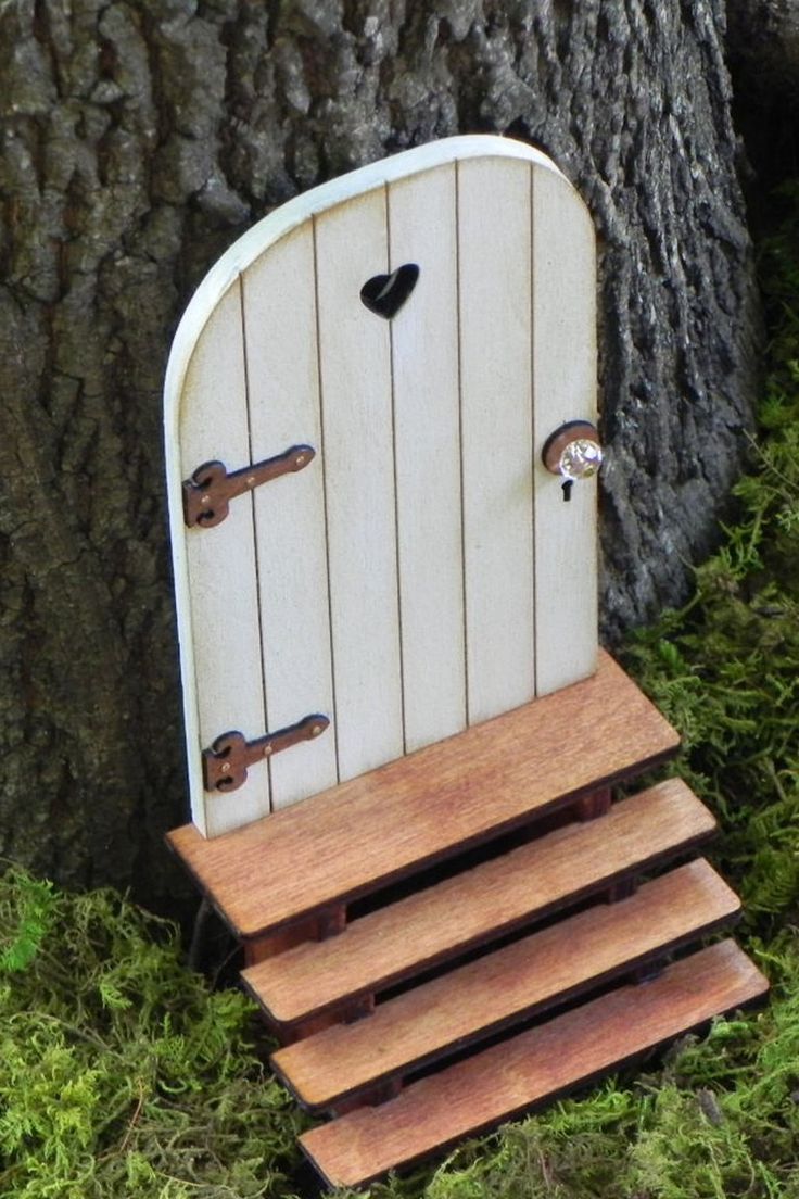 a small wooden door sitting on top of a green field next to a large tree