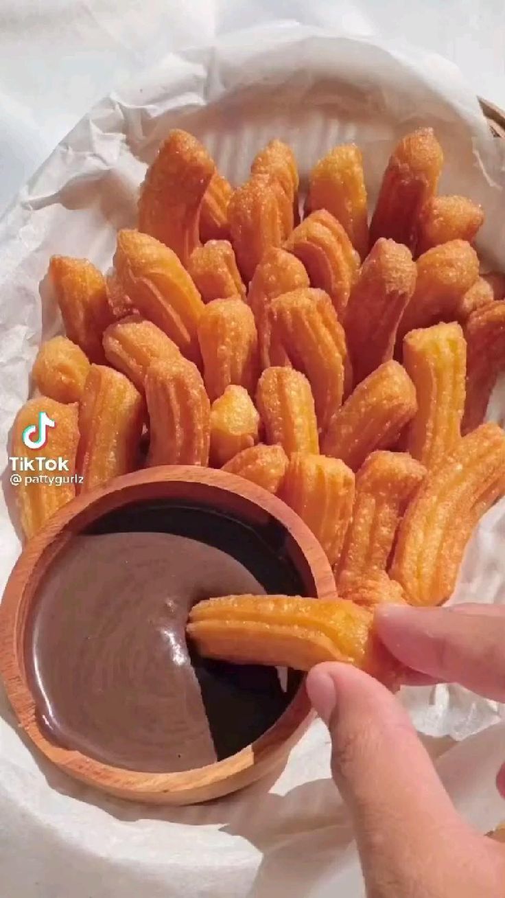 a person dipping sauce into churros in a bowl