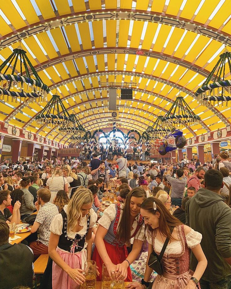 two girls in costume are serving themselves at a table full of food and people standing around