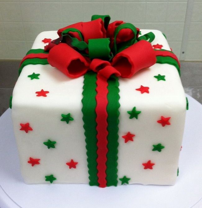 a white cake with red and green decorations on it's side, wrapped in fondant