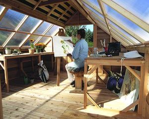 a woman sitting at a table in a greenhouse