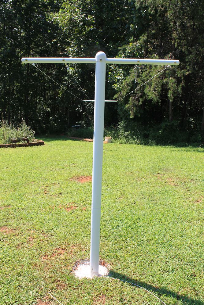 a white pole in the middle of a grassy field with trees in the back ground