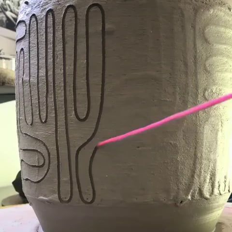 a clay pot that is sitting on a table with a pink string in the middle of it