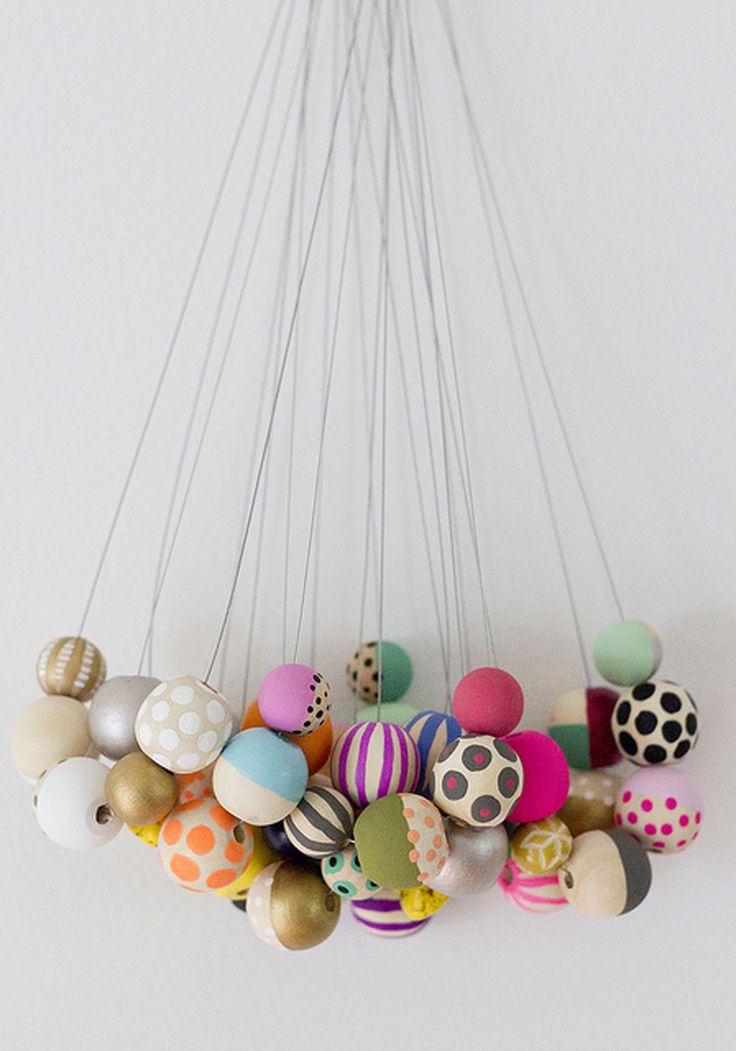 a bunch of different colored balls hanging from a ceiling light fixture with strings attached to it