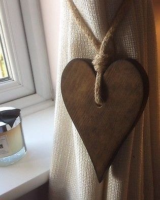 a wooden heart hanging on the side of a window sill next to a candle