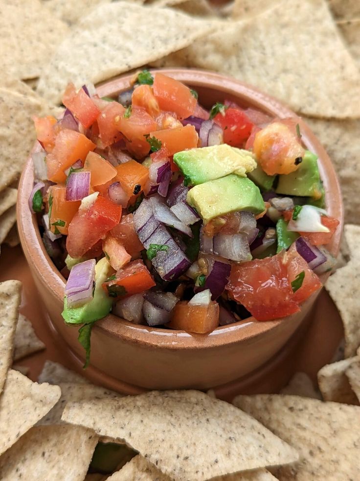 a bowl filled with salsa surrounded by tortilla chips