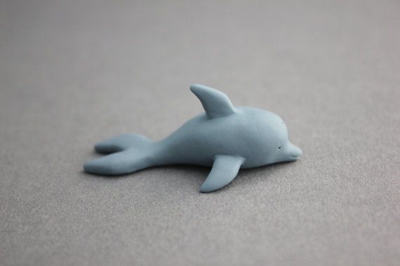 a toy dolphin laying on the ground with it's head turned to the side