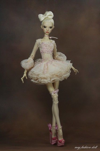 a doll is wearing a pink dress and high heeled shoes while standing in front of a brown background