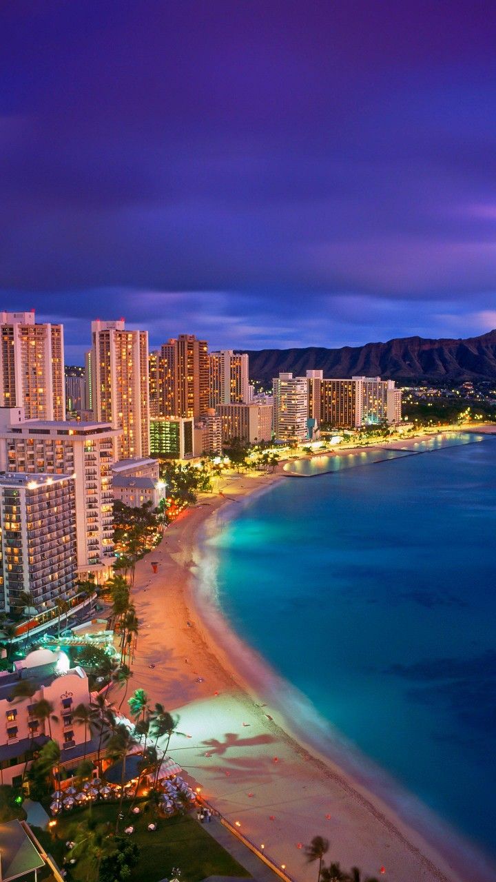 an aerial view of waikiki beach at night, with the city lights lit up