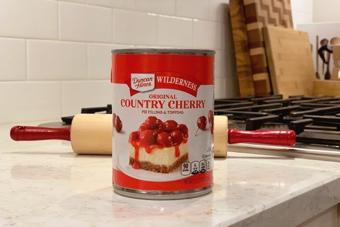 a can of country cherry cheesecake sitting on a kitchen counter next to a rolling pin