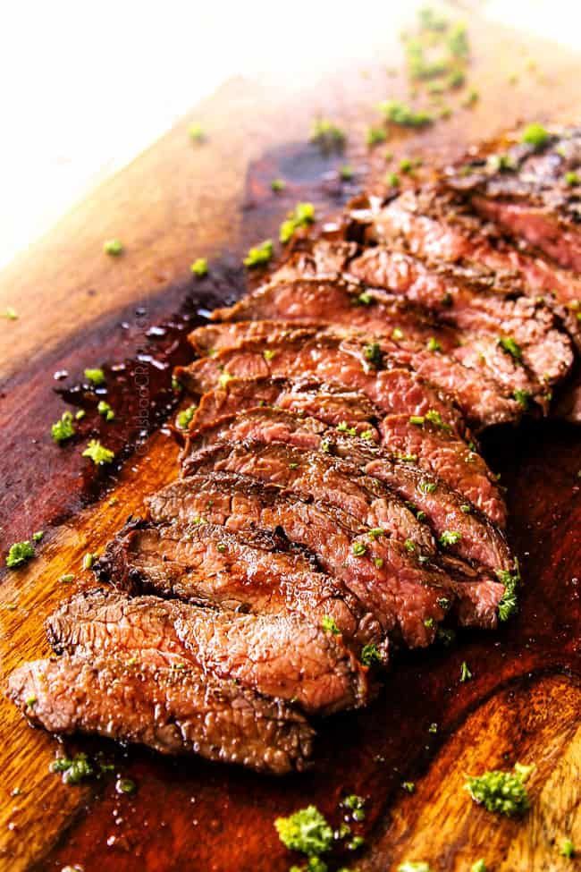 a steak on a cutting board with parsley sprinkled around it's edges