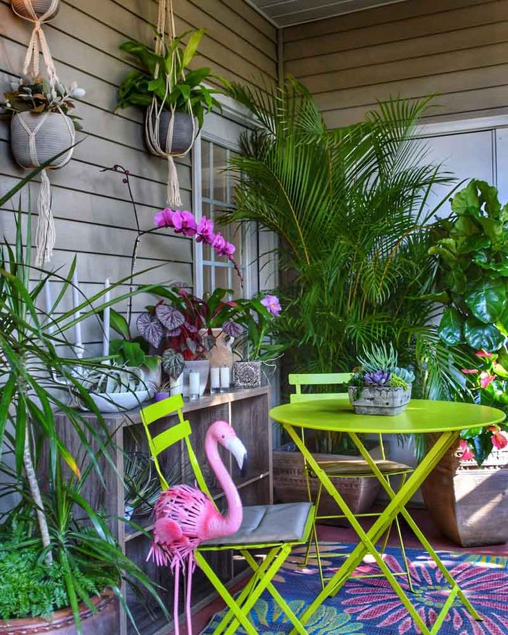 a pink flamingo sitting on top of a green chair next to a small table