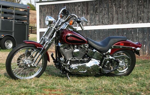 a red and black motorcycle parked in front of a wooden building with a trailer behind it