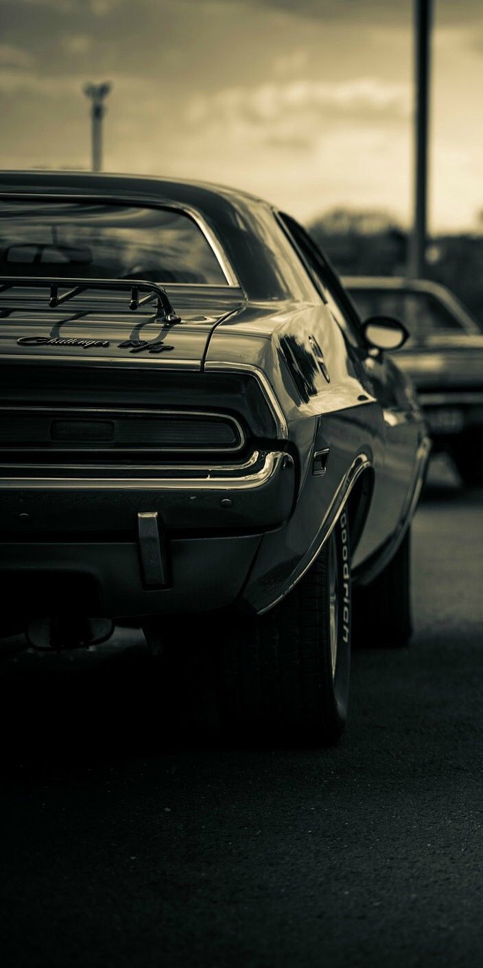 an old car parked in a parking lot next to another car with the hood up