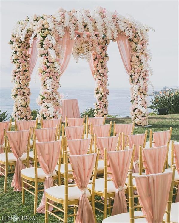 an image of a wedding with pink and white flowers on the arch over the aisle