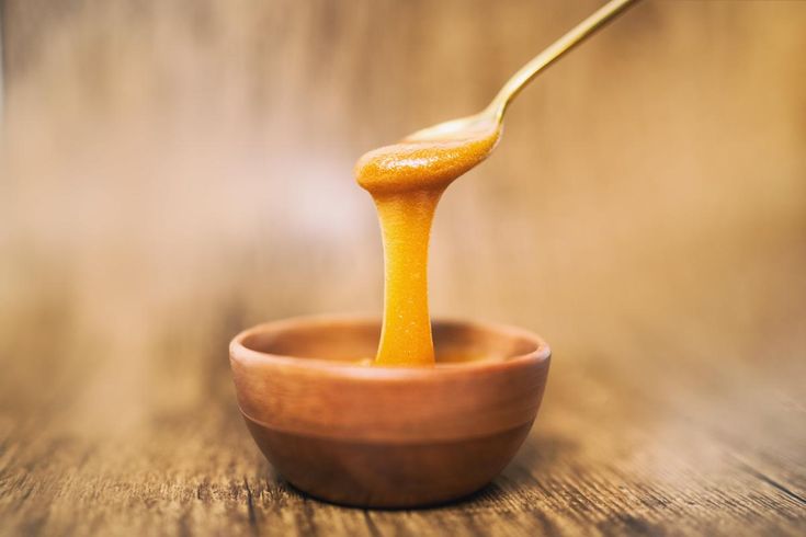 a wooden bowl filled with orange sauce being spooned into the small bowl on the table