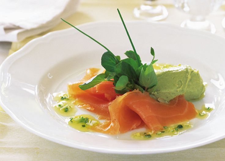 a white plate topped with salmon and guacamole on top of a table