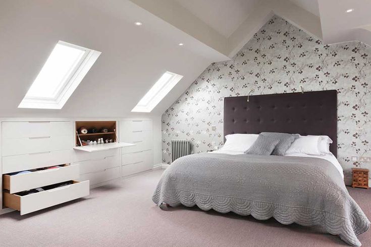 a bedroom with a bed, dressers and drawers in it's attic space