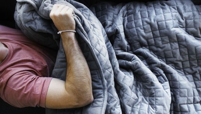 a man laying on top of a bed under a blanket