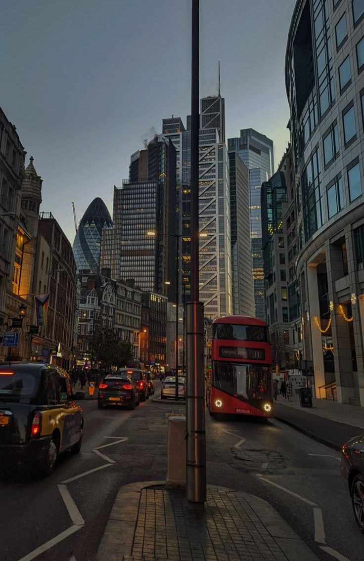 a city street filled with lots of traffic and tall buildings in the background at dusk