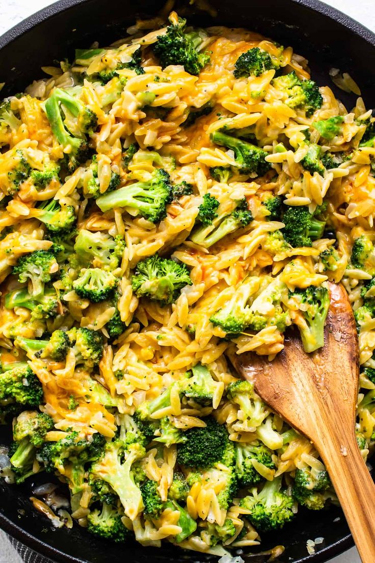 broccoli and noodles in a skillet with a wooden spoon