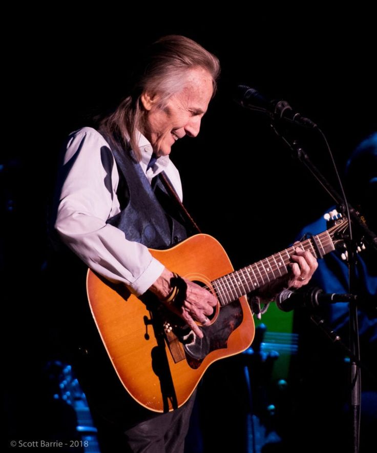 an older man is playing the guitar on stage