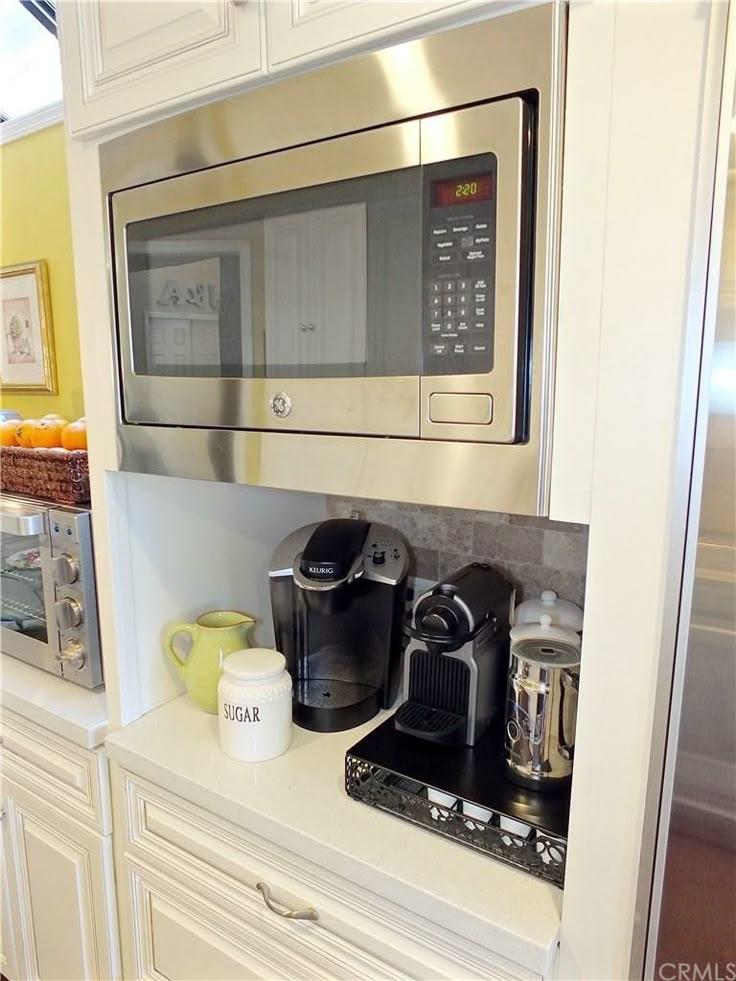 a microwave oven sitting on top of a counter next to a coffee pot and cup