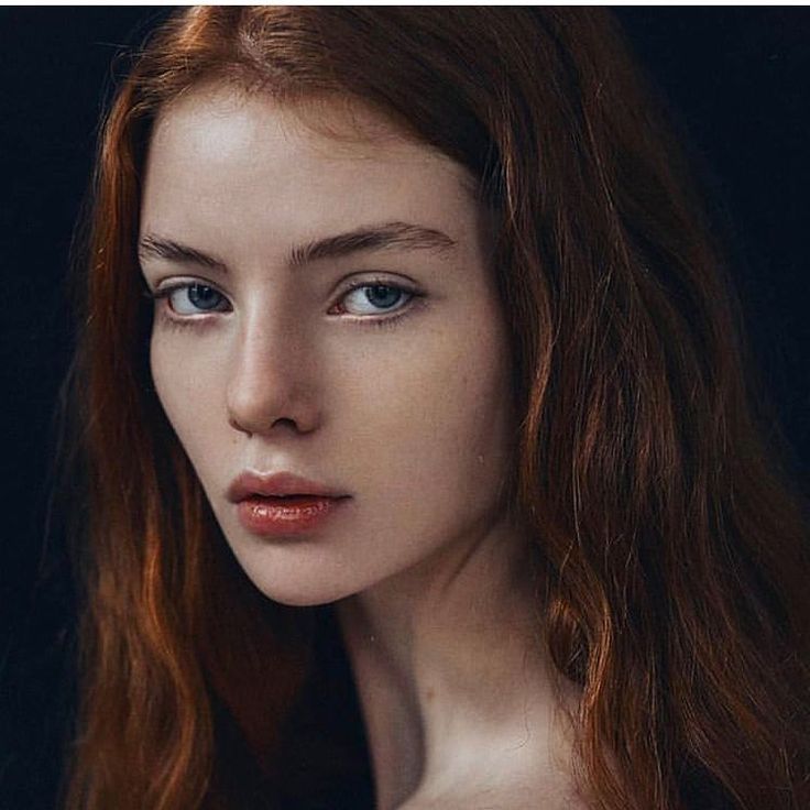 a woman with long red hair and blue eyes is posing for the photographer's portrait