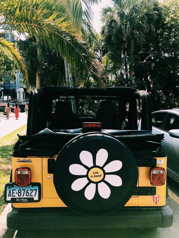 the back end of a yellow jeep with a flower painted on it