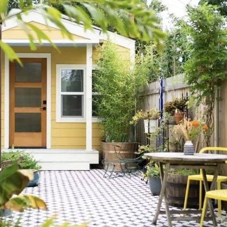 a small yellow house with a checkered floor and table in the front yard area