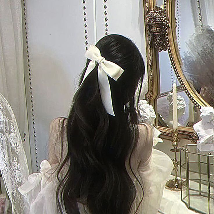 the back of a woman's head with long hair and a bow in her hair