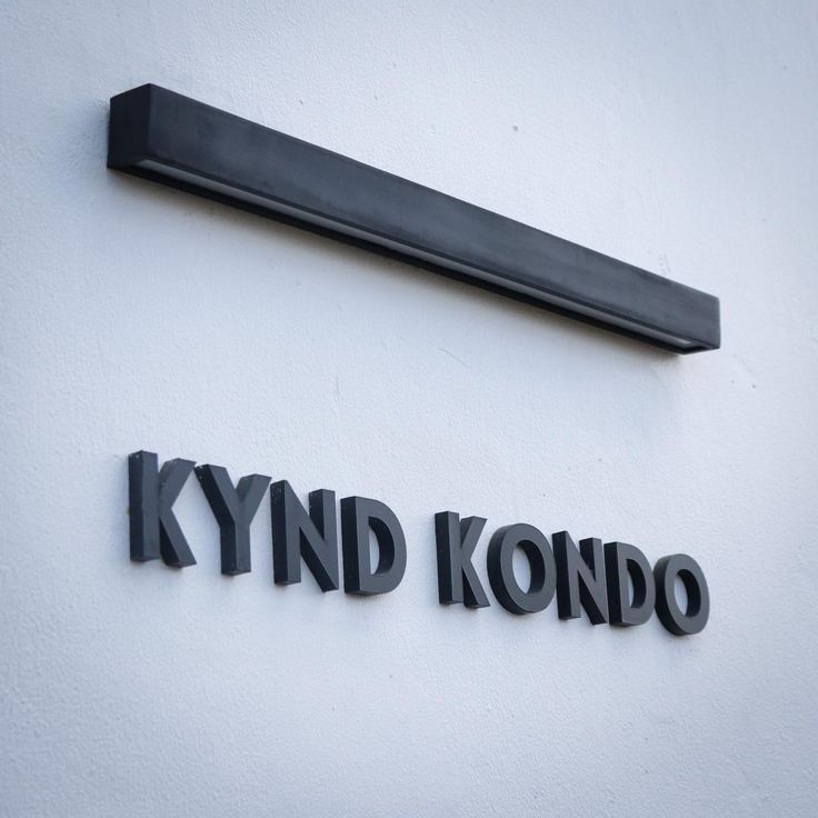 the sign for kynd kondo is on the side of a white building with black lettering